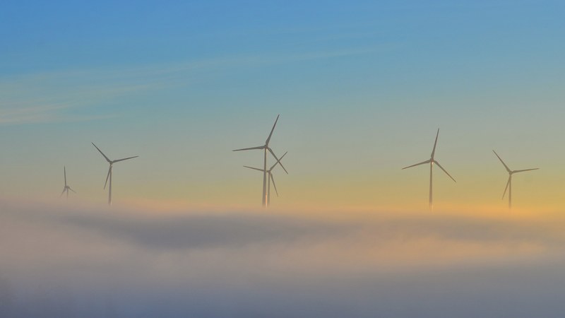 Wind turbines rise above a bank of low clouds in Europe.