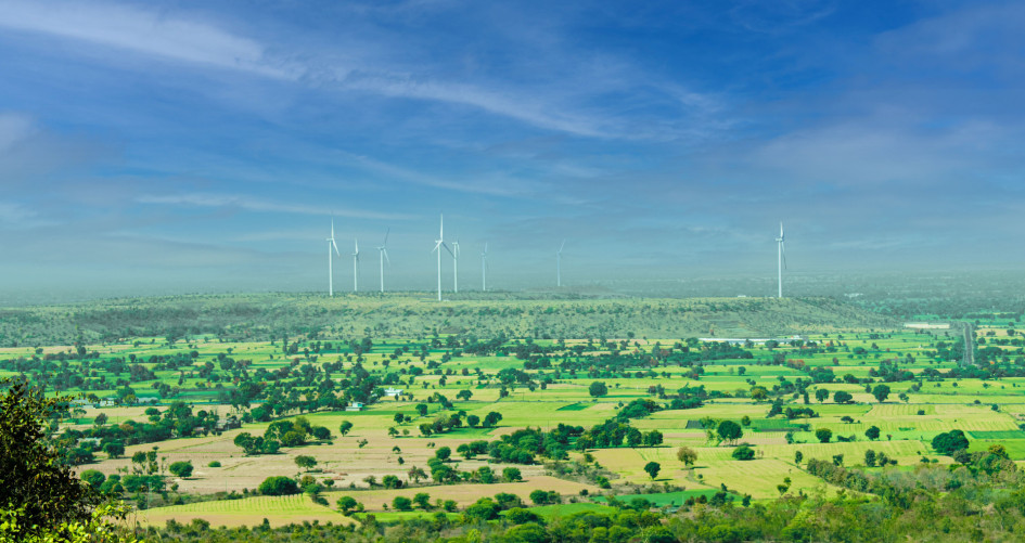 Wind turbines across a green agricultural landscape.