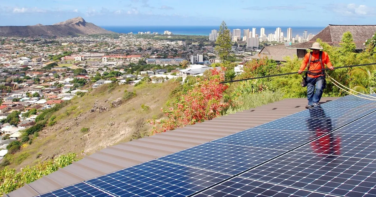 Worker installs rooftop solar panels above Honolulu, Hawaii.